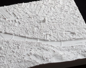Może przedstawiać: Szczegółowa, biała mapa 3D relief miasta, prezentująca skomplikowane układy budynków i ulic. Mapa zawiera rzekę i mosty, z teksturowaną powierzchnią. Projekt to monochromatyczna, architektoniczna reprezentacja.
