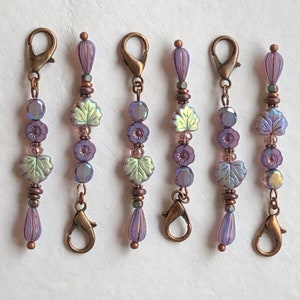 May include: Five purple and green beaded charms with a bronze clasp at each end. The charms are made with small glass beads and metal accents.