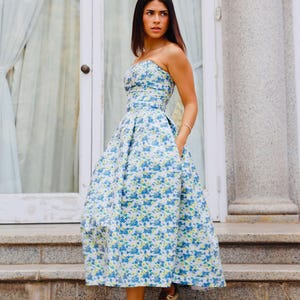 This stunning cocktail dress features a sweetheart neckline that adds a sophisticated touch to your special occasions. It is crafted in a beautiful blue brocade fabric adorned with delicate flower prints.
