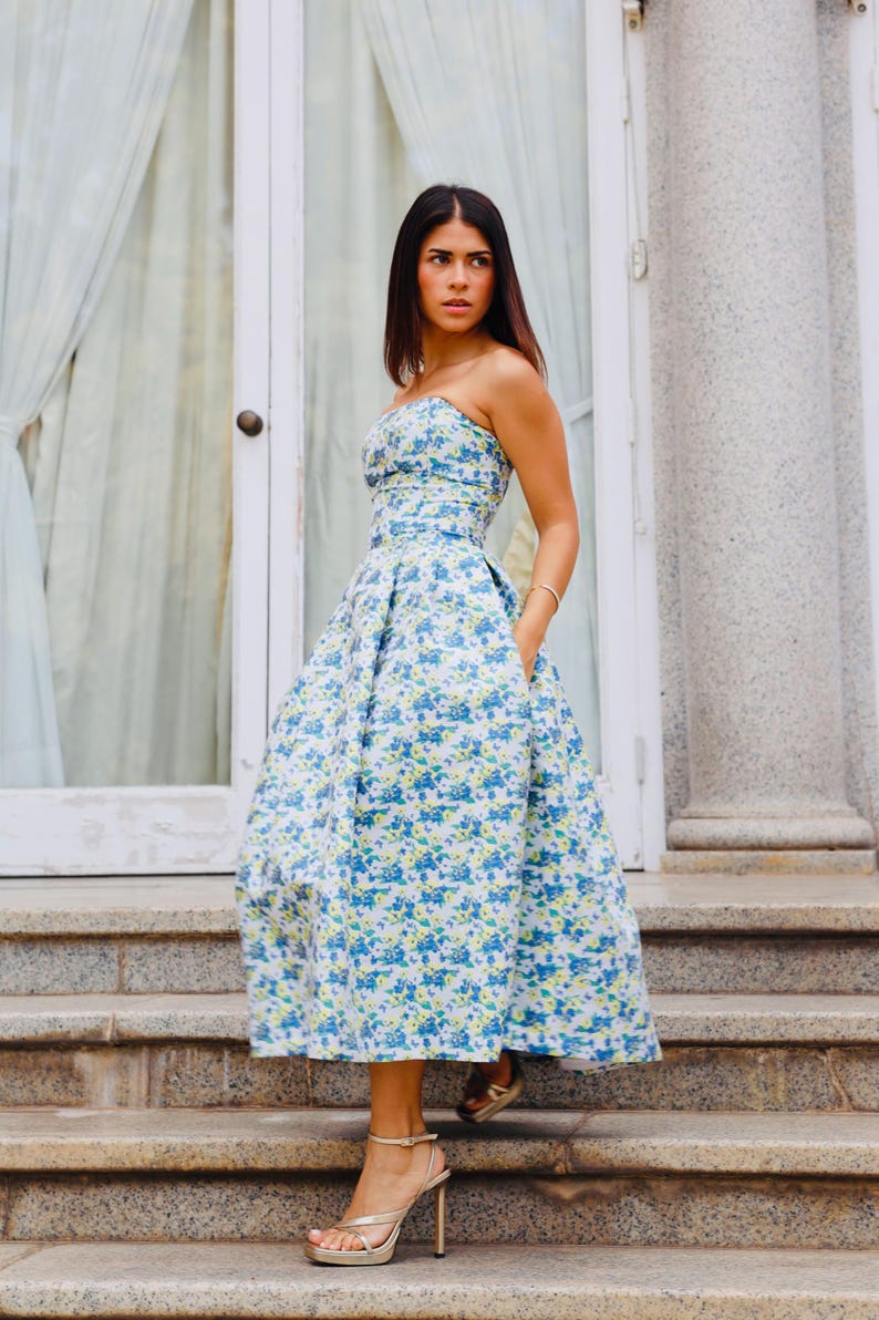 This stunning cocktail dress features a sweetheart neckline that adds a sophisticated touch to your special occasions. It is crafted in a beautiful blue brocade fabric adorned with delicate flower prints.