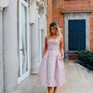 You have an invitation to a wedding, graduation party, or cocktail event. Our model is wearing a beautiful coral dress with a lovely floral design and an open back, perfect for your big day.
