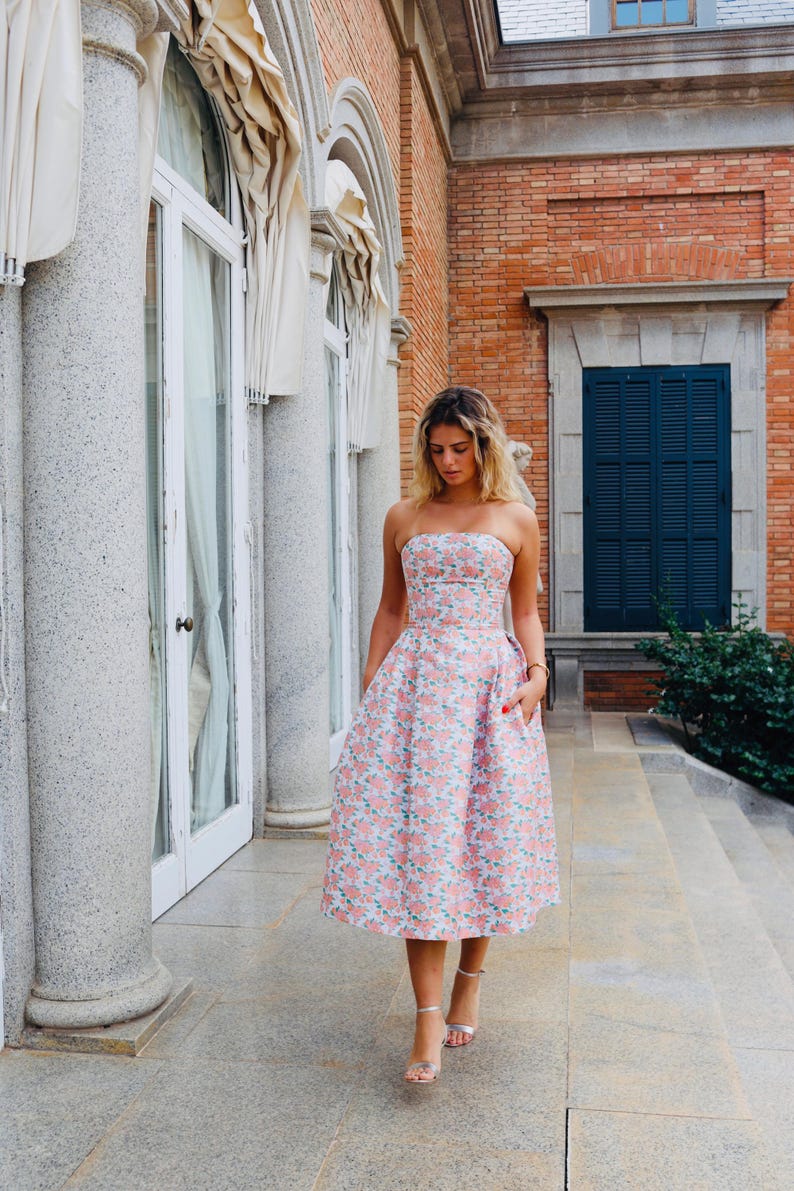 You have an invitation to a wedding, graduation party, or cocktail event. Our model is wearing a beautiful coral dress with a lovely floral design and an open back, perfect for your big day.