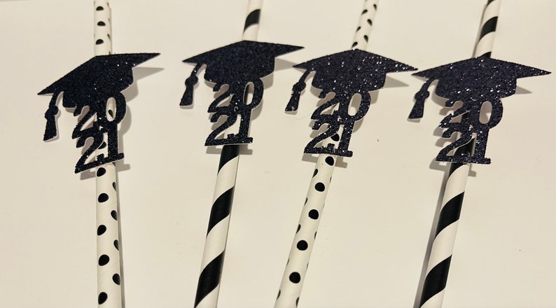 Puede incluir: Conjunto de cinco pajitas rayadas en blanco y negro con gorros de graduaci&oacute;n de purpurina negra y el a&ntilde;o 2021 en cada gorro.