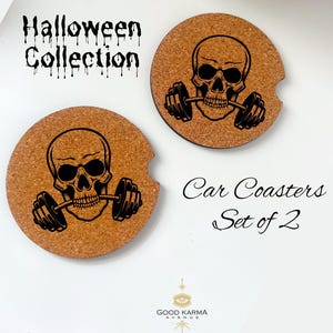 May include: Set of two car coasters with a Halloween theme. Each coaster is round and made of cork, featuring a black skull graphic lifting a barbell. The text "Halloween Collection" and "Car Coasters Set of 2" are also visible.