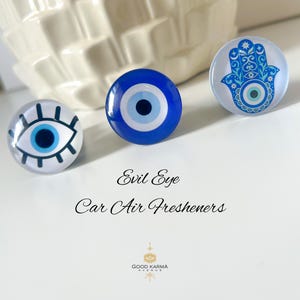 Könnte beinhalten: Drei runde Auto-Lufterfrischer mit Evil Eye- und Hamsa-Hand-Designs. Die Evil Eye-Lufterfrischer haben ein blau-weißes Augendesign. Der Hamsa-Hand-Lufterfrischer hat eine blaue Hand mit einem Auge in der Mitte.