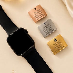 May include: A black smartwatch with a black strap is shown with three metal medical alert tags. The tags are in copper, silver, and gold. Each tag has the name "Sarah Smith" and medical information, including allergies and emergency contact details.