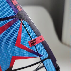 May include: A blue and red windsurf sail with a black frame and a white label that says "SUPER STAR" with a red arrow pointing to the right.