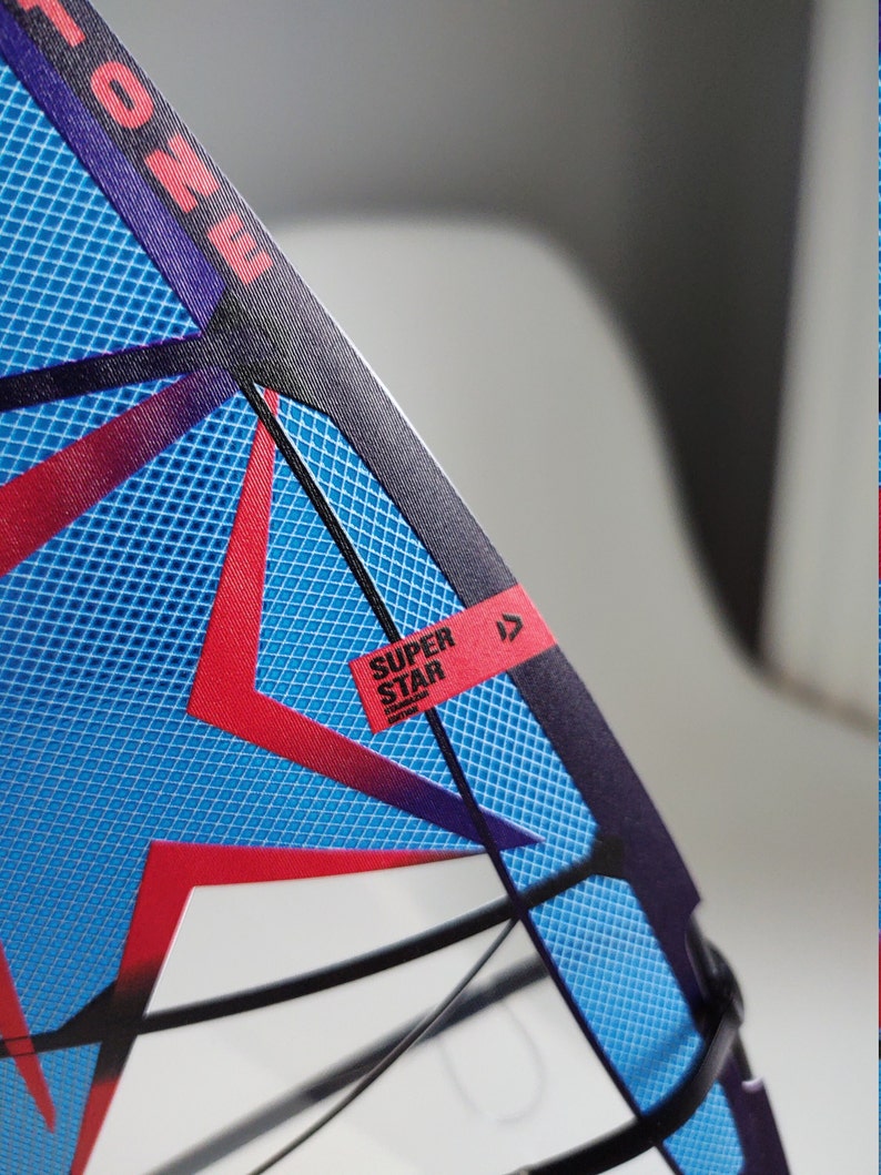 May include: A blue and red windsurf sail with a black frame and a white label that says "SUPER STAR" with a red arrow pointing to the right.