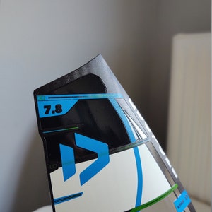 K&ouml;nnte beinhalten: Ein schwarz-wei&szlig;er Drachen mit blauem und gr&uuml;nem Design. Der Drachen hat die Nummer "7.8" aufgedruckt.
