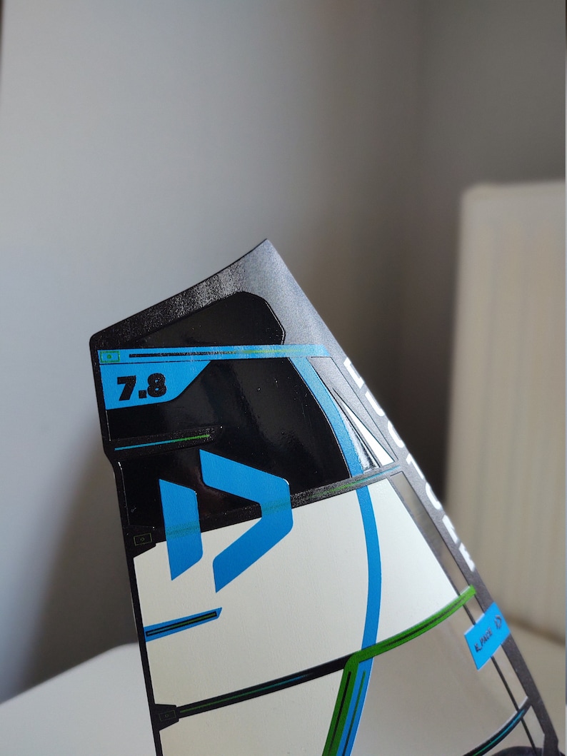 K&ouml;nnte beinhalten: Ein schwarz-wei&szlig;er Drachen mit blauem und gr&uuml;nem Design. Der Drachen hat die Nummer "7.8" aufgedruckt.