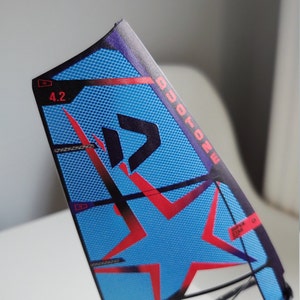 May include: A blue and red windsurf sail with a white star and the text "DUOTONE" and "SUPER STAR" printed on it. The sail is numbered "4.2".