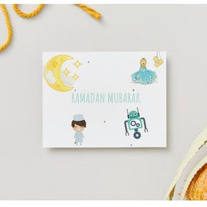 Könnte beinhalten: Eine weiße Karte mit den Worten "Ramadan Mubarak" in blauer Schrift. Auf der Karte befinden sich vier Illustrationen: ein gelber Halbmond mit weißen Wolken, ein Mädchen in einem blauen Kleid, ein Junge in einem weißen Gewand und ein grüner Roboter.