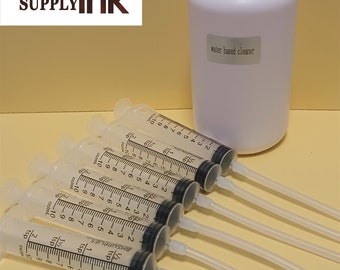 May include: Six clear plastic syringes with black markings and attached clear tubes, next to a white bottle labeled "water based cleaner".