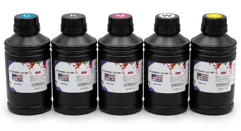 May include: Five black plastic bottles containing UV curable LED ink, each topped with a colored cap labeled C, K, M, W, or Y. The white labels feature a colorful paint splash graphic, the text UV CURABLE LED INK, and a small USA flag icon.