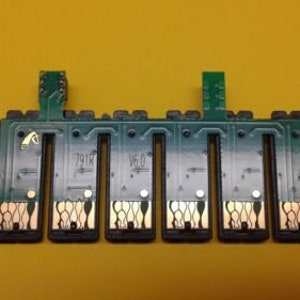 May include: A green and black electronic component with multiple rectangular slots and gold-colored detailing. The component has two vertical connectors and the text "791R" and "V6.0" printed on it. The background is a solid yellow.