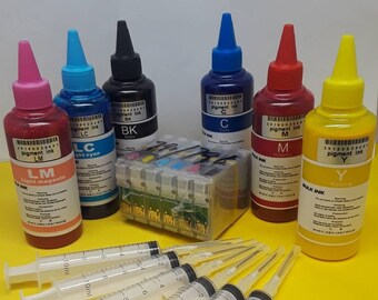 May include: A collection of ink bottles in various colors, including magenta, cyan, black, and yellow, with matching syringes. The bottles are labeled with color codes and the text "pigment ink". A printer cartridge is also present.