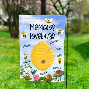 May include: A blue and yellow garden flag with a beehive and the text "Memas lovebugs". The beehive has the names of children written around it: Mason, Livason, Cooper, Paisley, Kennan, Wyatt, and Ford.