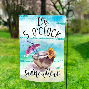 Puede incluir: Una bandera de jardín azul y blanca con el texto "It's 5 O'Clock Somewhere" y una ilustración de acuarela de un coco con una pajita y una sombrilla.