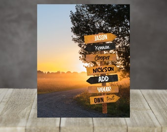 May include: A rustic wooden signpost with multiple arrows pointing in different directions. Each arrow has a name written on it, including "Jason", "Kennan", "Cooper", "Nick", "Add", "Your", and "Own text". The signpost is set against a backdrop of a sunset over a dirt road.