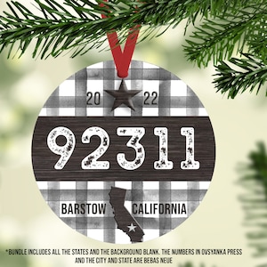 Op de afbeelding: Een ronde, wit-zwarte geruite kerstbal met een houtnerf achtergrond. De bal heeft de nummers "92311", de woorden "Barstow, Californië" en een ster. De bal is versierd met een rood lint.