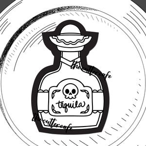 May include: A black and white cookie cutter shaped like a tequila bottle with a sombrero on top. The bottle label features a skull graphic and the word tequila. The design includes the text the cutter cafe freshly brewed designs.