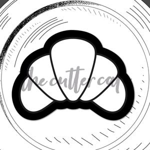 Può includere: Un tagliabiscotti nero a forma di croissant su un piatto bianco con un disegno abbozzato. Le parole "the cutter cafe" e "freshly brewed designs" sono in alto. La parola "croissant" è in basso.