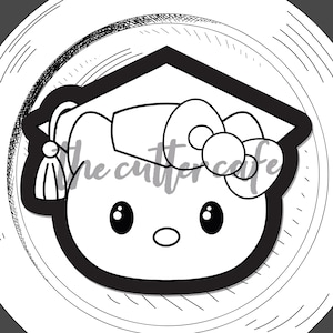 May include: Black and white cookie cutter shaped as a graduation cap on a cat face. The text "grad hat kitty" is at the bottom. The Cutter Cafe logo is at the top right. The design is on a white plate.