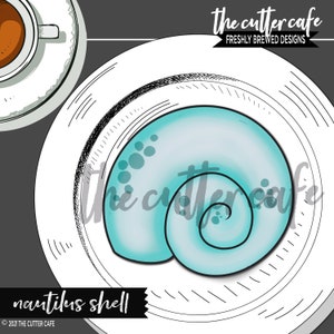 May include: A light blue nautilus shell cookie cutter on a white plate. The cutter is shaped like a nautilus shell with a spiral pattern. The text "The Cutter Cafe" is visible in the background.