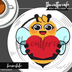 May include: A yellow and black bee with big eyes and a smile holds a red heart in its arms. The bee is on a white plate with a black and white pattern. The text "bumble" is below the bee.