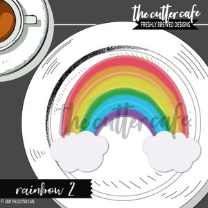 May include: A colorful rainbow design with white clouds on a white plate. The rainbow features red, orange, yellow, green, blue, and purple hues. The plate is next to a cup of coffee. The text "rainbow 2" is at the bottom.
