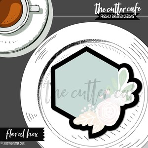 Puede incluir: Un cortador de galletas floral hexagonal con un contorno negro, centro azul claro y detalles florales. El cortador est&aacute; sobre un plato blanco con una taza de caf&eacute; en la esquina superior izquierda. El texto "the cutter cafe" est&aacute; arriba.