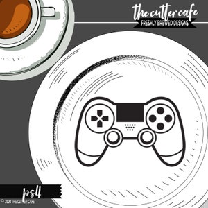 May include: Black and white illustration of a video game controller on a white plate with a black and white sketched border. The text "the cutter cafe" and "freshly brewed designs" is above the plate. The text "ps4" is below the plate.