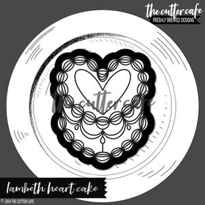 May include: Black and white line art illustration of a heart-shaped cake with decorative frosting. The cake is on a white plate with a black outline. The text "Lambeth heart cake" is below the plate.
