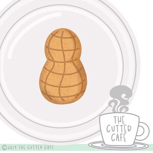 Puede incluir: Cortador de galletas con forma de cacahuete marrón claro con un patrón de cuadrícula, centrado en un plato blanco. El logotipo de The Cutter Cafe está en una taza de café. Copyright "© 2019 THE CUTTER CAFE".