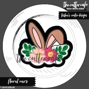 Könnte beinhalten: Ein Ausstecher in Form von Hasenohren mit rosa und grünen floralen Akzenten. Der Ausstecher befindet sich auf einem weißen Hintergrund mit schwarzen Linien.