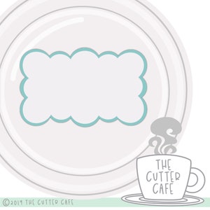 May include: A white plate with a gray and white striped pattern. A blue cloud-shaped frame is in the center of the plate. A gray coffee cup with the text "THE CUTTER CAFE" is on a saucer below the plate.