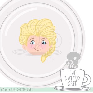 May include: A white ceramic mug with the text "THE CUTTER CAFE" in black lettering. The mug is filled with a white liquid and has steam rising from it. A cartoon image of a blonde woman's head with blue eyes is in the background.