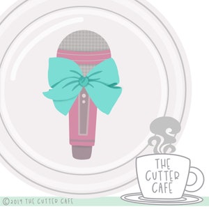 May include: A pink microphone with a turquoise bow tied around it. The microphone is in front of a white plate with a gray circle pattern. The text "THE CUTTER CAFE" is on a gray coffee cup with steam coming from it.