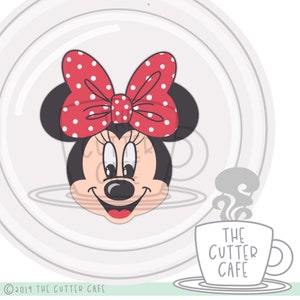 May include: A cartoon illustration of Minnie Mouse with a red bow with white polka dots. The image includes the text "THE CUTTER CAFE".