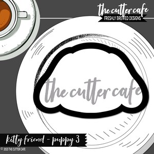 May include: Black and white illustration of a puppy head with the text "The cutter cafe" in grey lettering. The image is on a white plate with a black and white patterned border.
