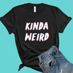 May include: Black t-shirt with the text "Kinda Weird" in a glitchy, colorful font.