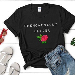 May include: Black t-shirt with white text that reads "Phenomenally Latina" and a red rose graphic.