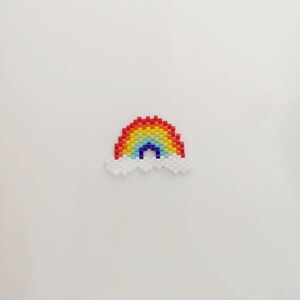 May include: A rainbow made of colorful beads with a white cloud on each side.