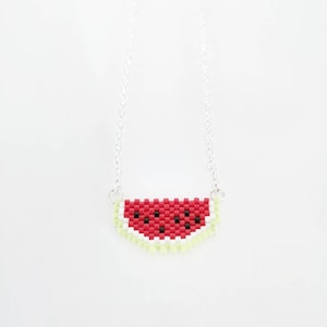 May include: A silver chain necklace with a watermelon slice pendant made of red, white, and green beads.