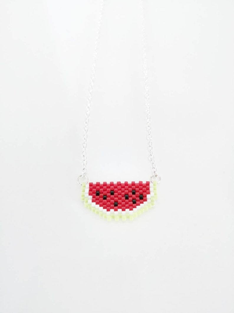 May include: A silver chain necklace with a watermelon slice pendant made of red, white, and green beads.