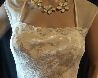 May include: A white satin dress with a lace bodice and a gold beaded belt. The dress has a scoop neckline and cap sleeves.
