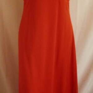 May include: A long, sleeveless, red maxi dress with a sweetheart neckline. The dress has a fitted bodice and a flowing skirt.