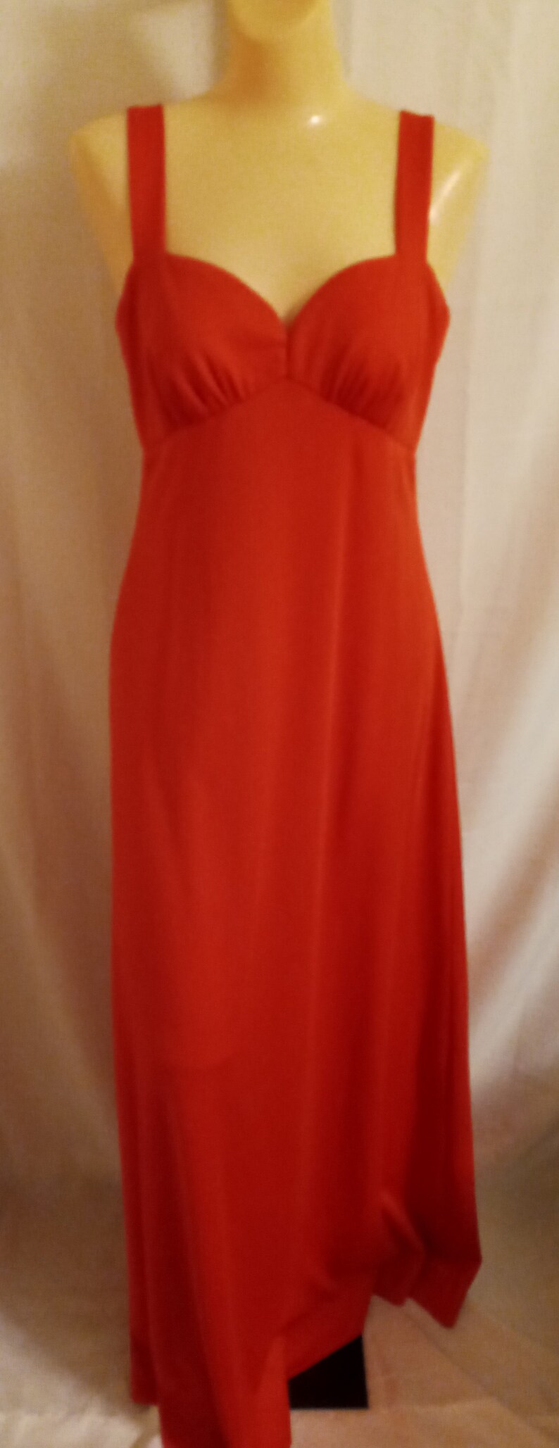 May include: A long, sleeveless, red maxi dress with a sweetheart neckline. The dress has a fitted bodice and a flowing skirt.