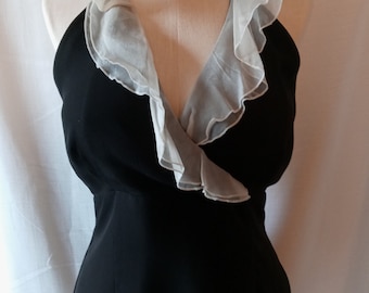 May include: A black halter dress with a white, ruffled collar. The dress is displayed on a mannequin. The collar has a sheer, layered appearance. The dress has a simple, elegant design, suitable for formal occasions.