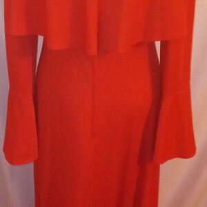 May include: A long-sleeved red dress with a ruffled neckline and bell sleeves.